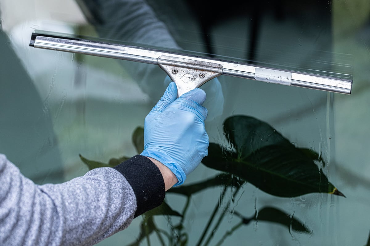 Professional cleaning worker washing double-glazed windows with squeegee and microfiber cloth