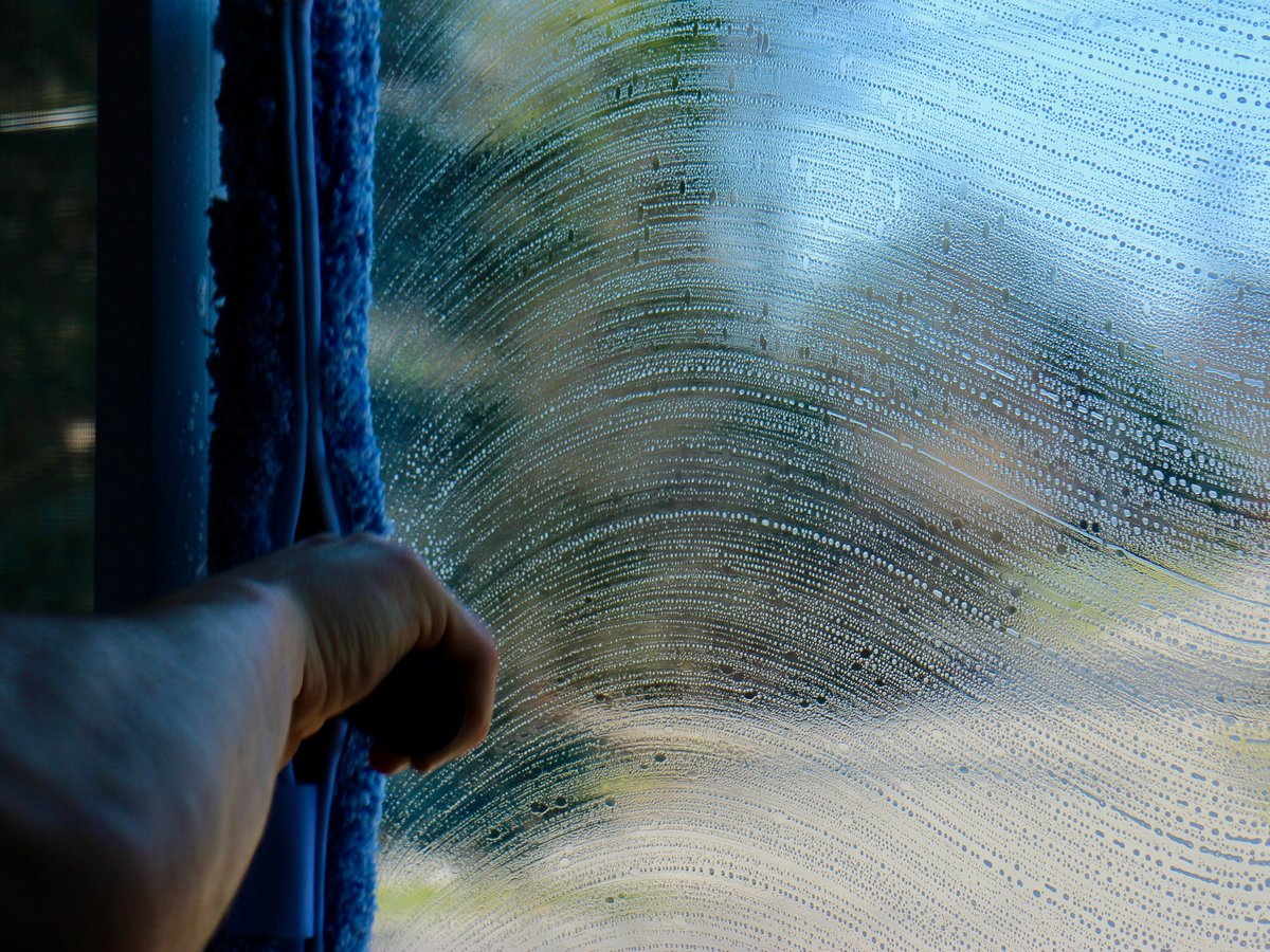 Close-up of a cleaning brush scrubbing a wet, soapy surface with blue and white streaks visible