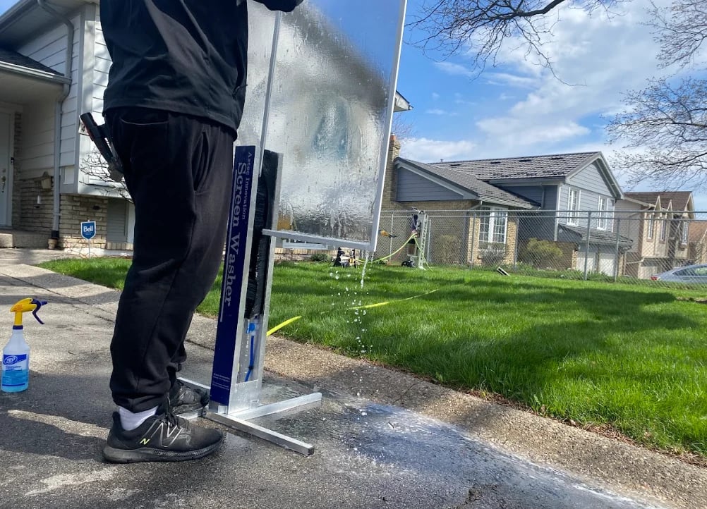 Portable solar panel setup in driveway with extension cords and power equipment, bare trees and road visible in background