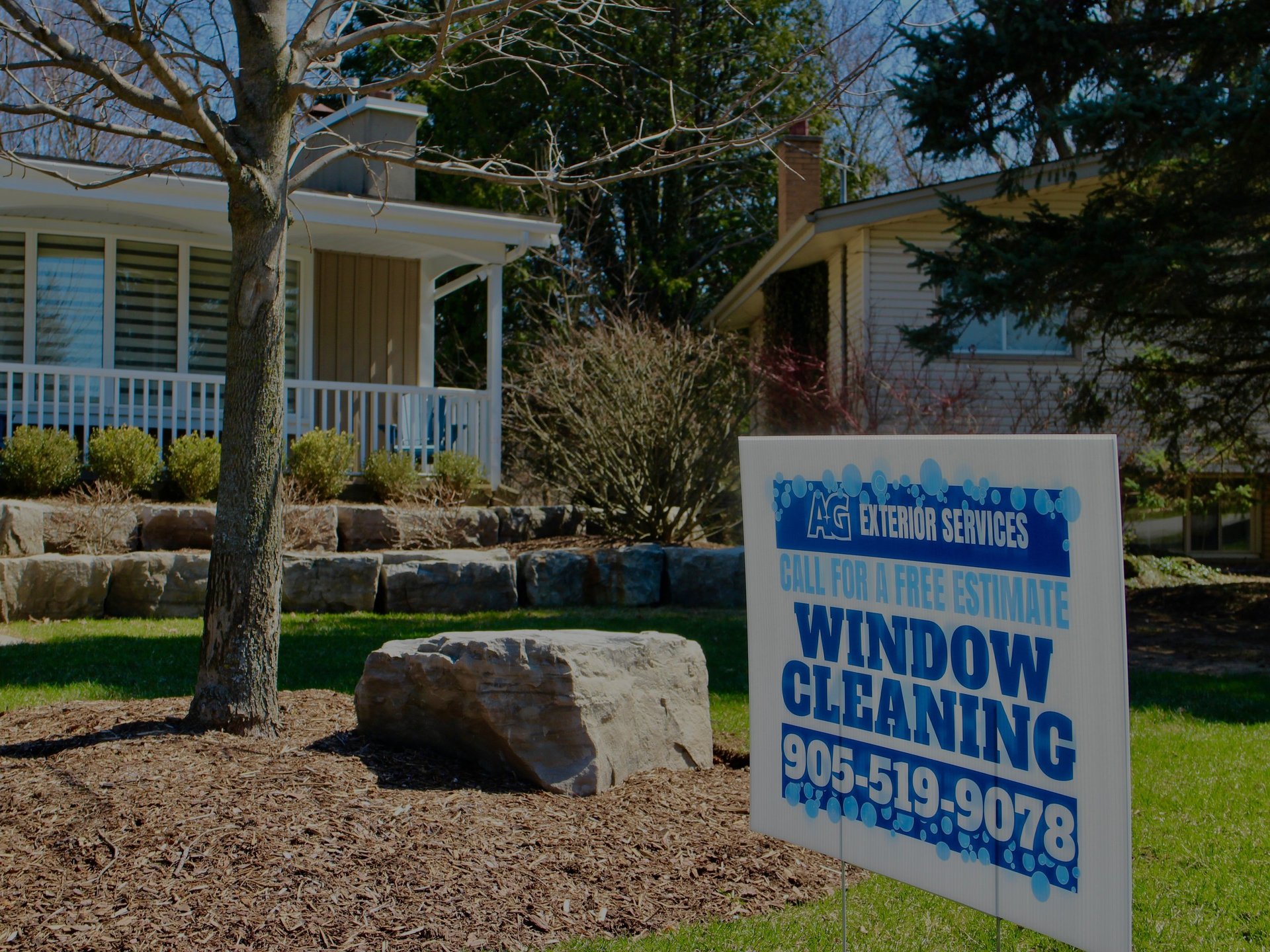 Exterior home with blue window cleaning service sign displaying phone number 905-519-8079 in front yard